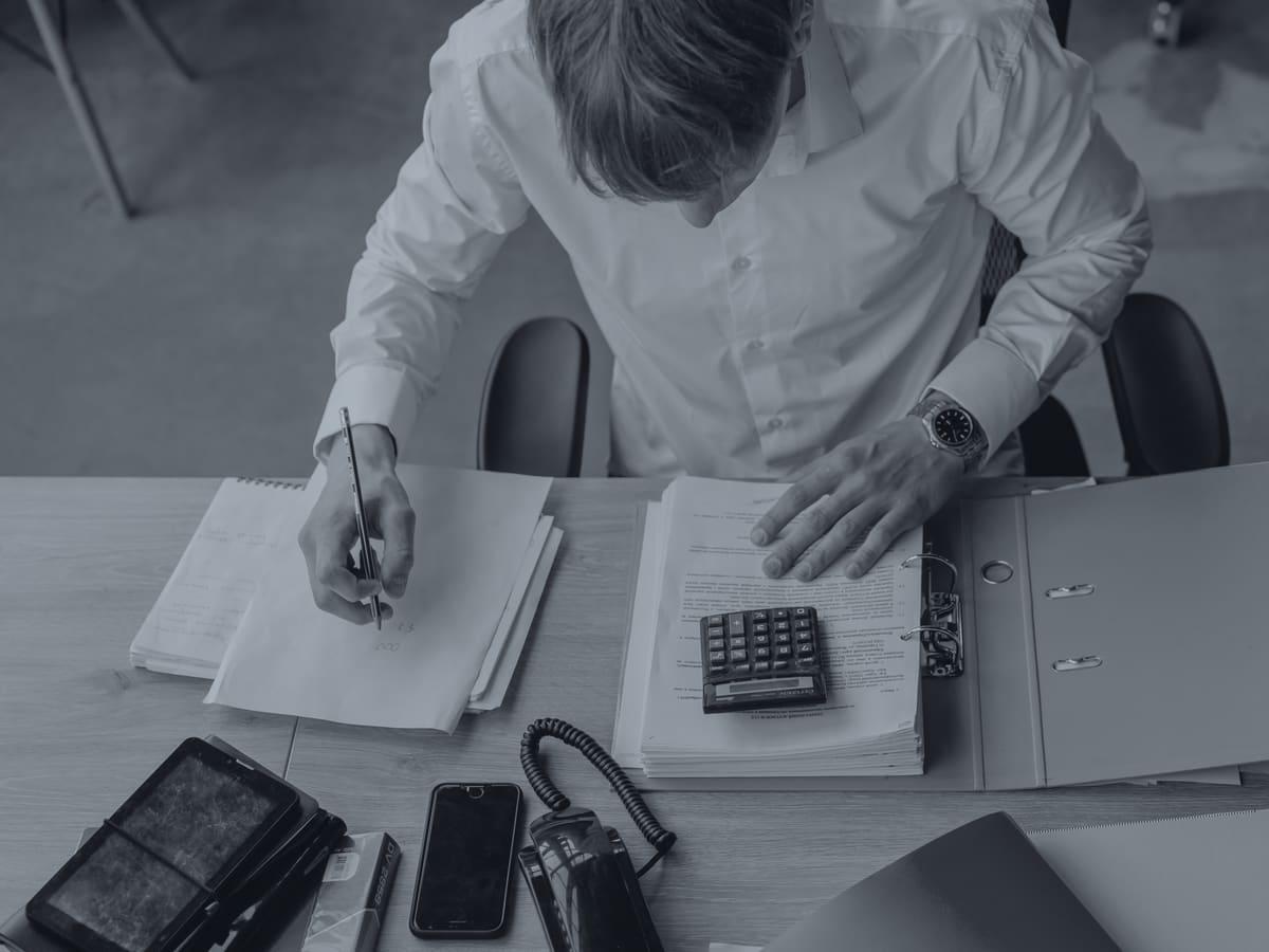 Business owner working through paperwork with a calculator at a desk
