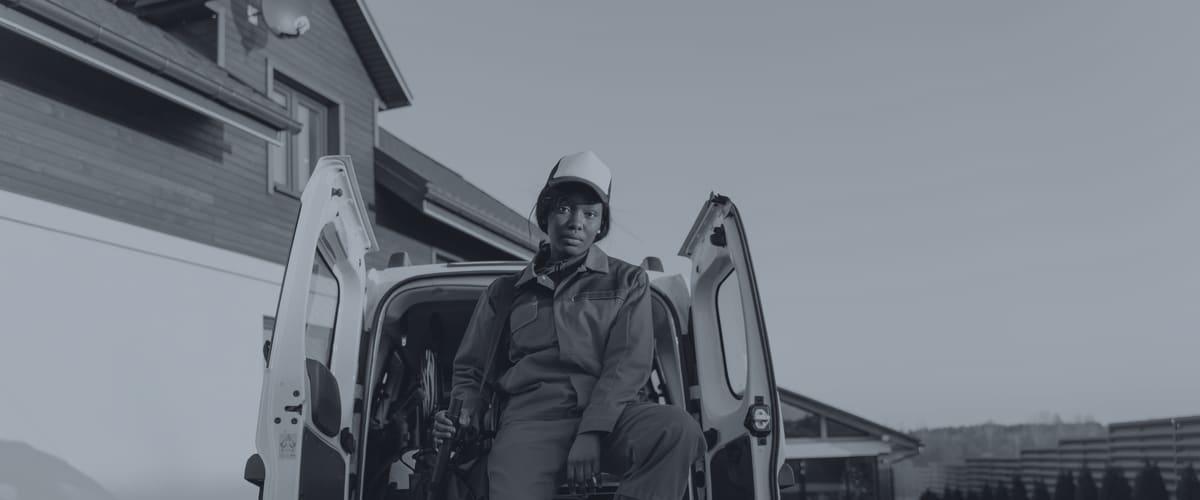 Worker in a hard hat and hi-vis jacket beside a white work van