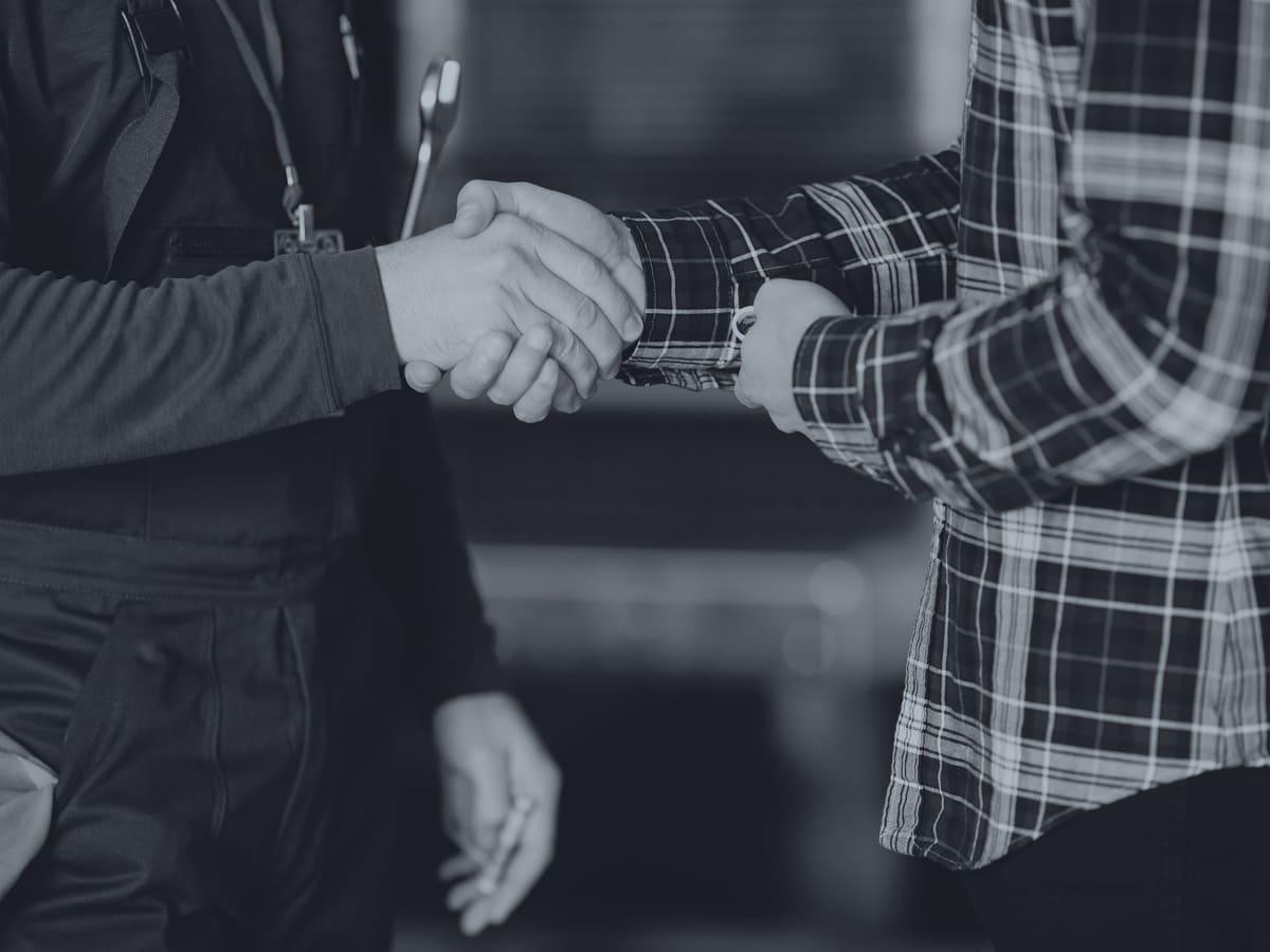 Two people shaking hands in a workshop