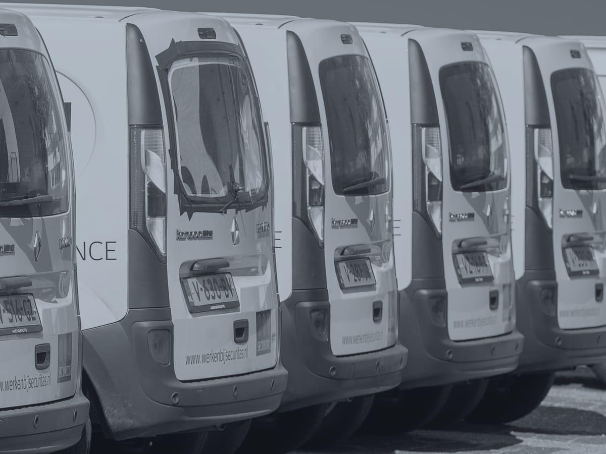 A row of identical white work vans parked outdoors